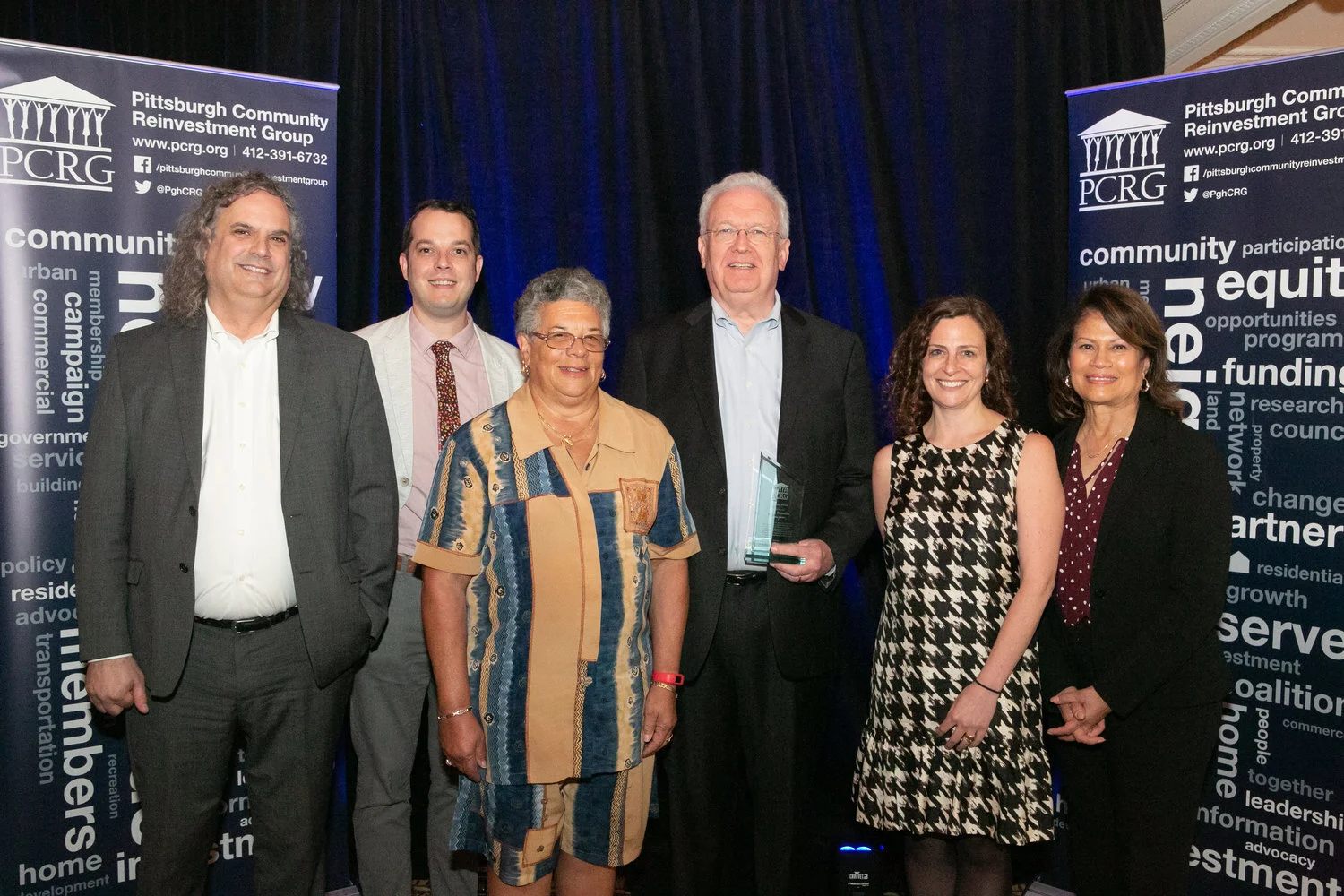 Mark Peterson, fourth from left and holding an award, with five people at a Pittsburgh Community Reinvestment Group event.