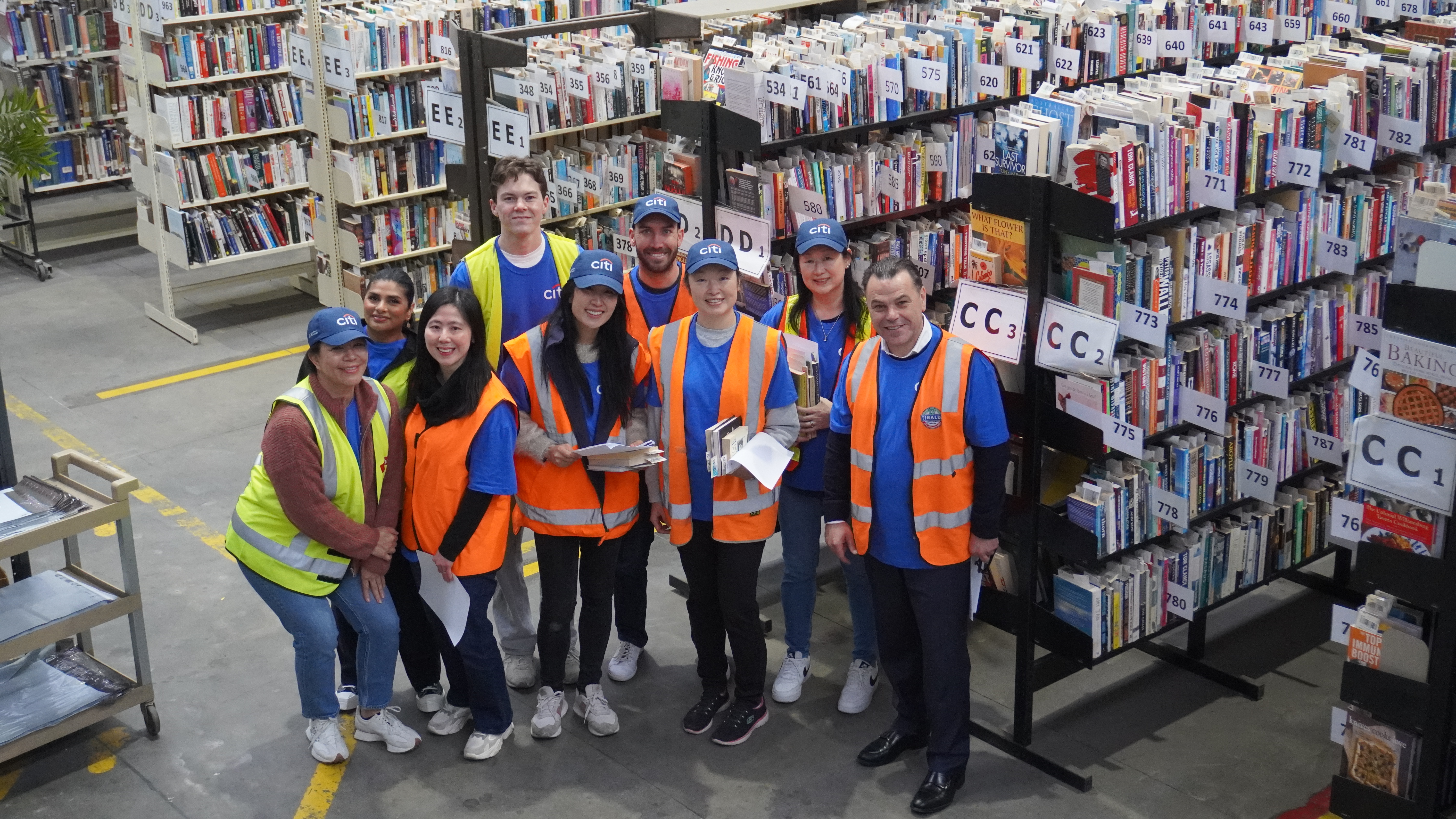 Mark Woodruff, at right, with Citi volunteers among book shelves at the Brotherhood Books warehouse