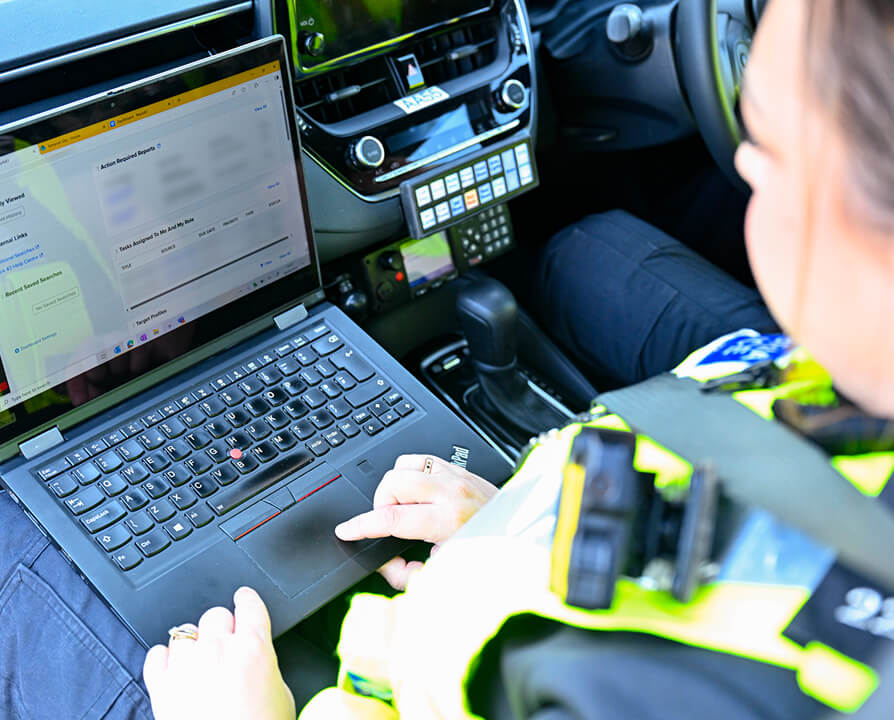 An officer works on a laptop inside a patrol vehicle, in a photograph published by Mark43.