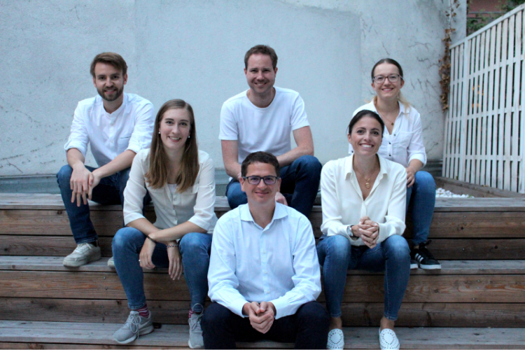 Six inoqo founders seated together on outdoor wooden steps