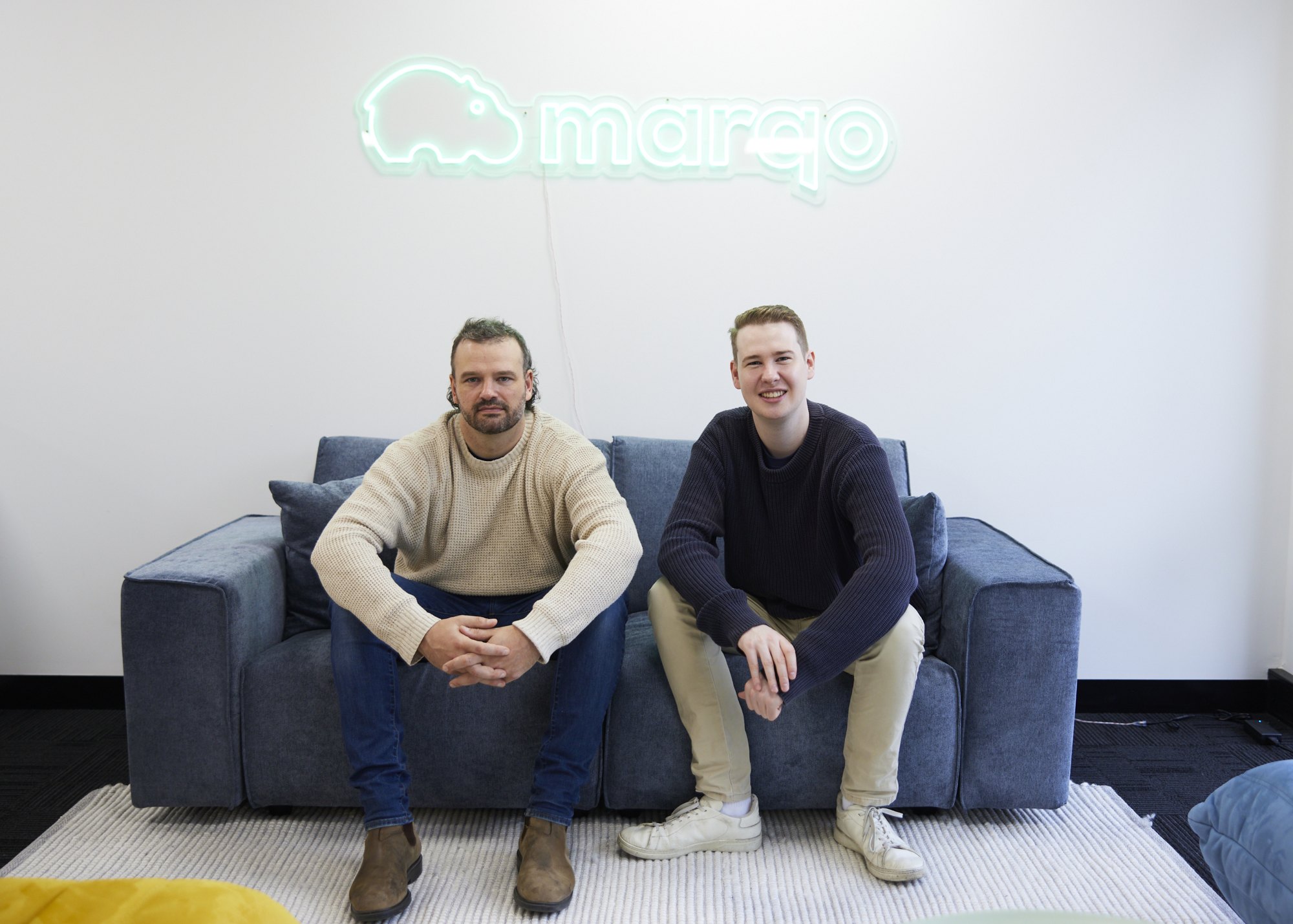 Marqo founders Tom Hamer and Jesse Clark seated beneath the company sign