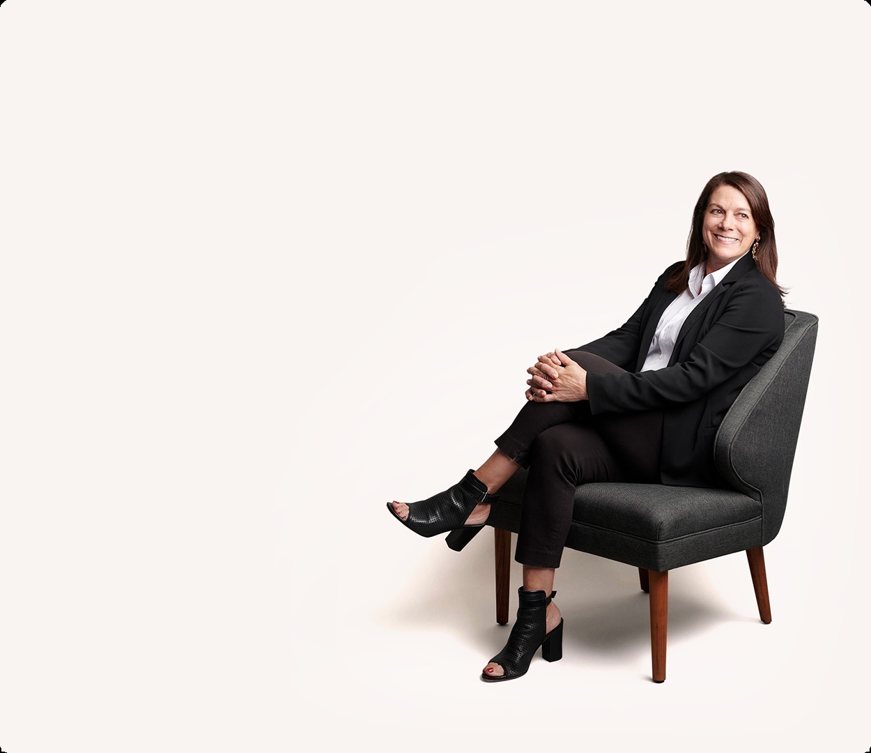 Martha Marchesi seated in a gray chair against a light studio background