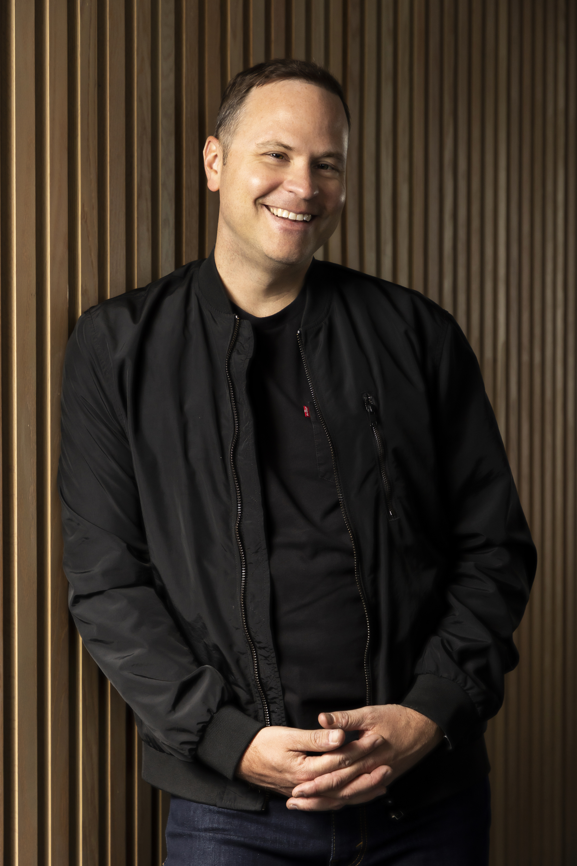 Martin Aubut smiling in front of a warm wood-panelled wall