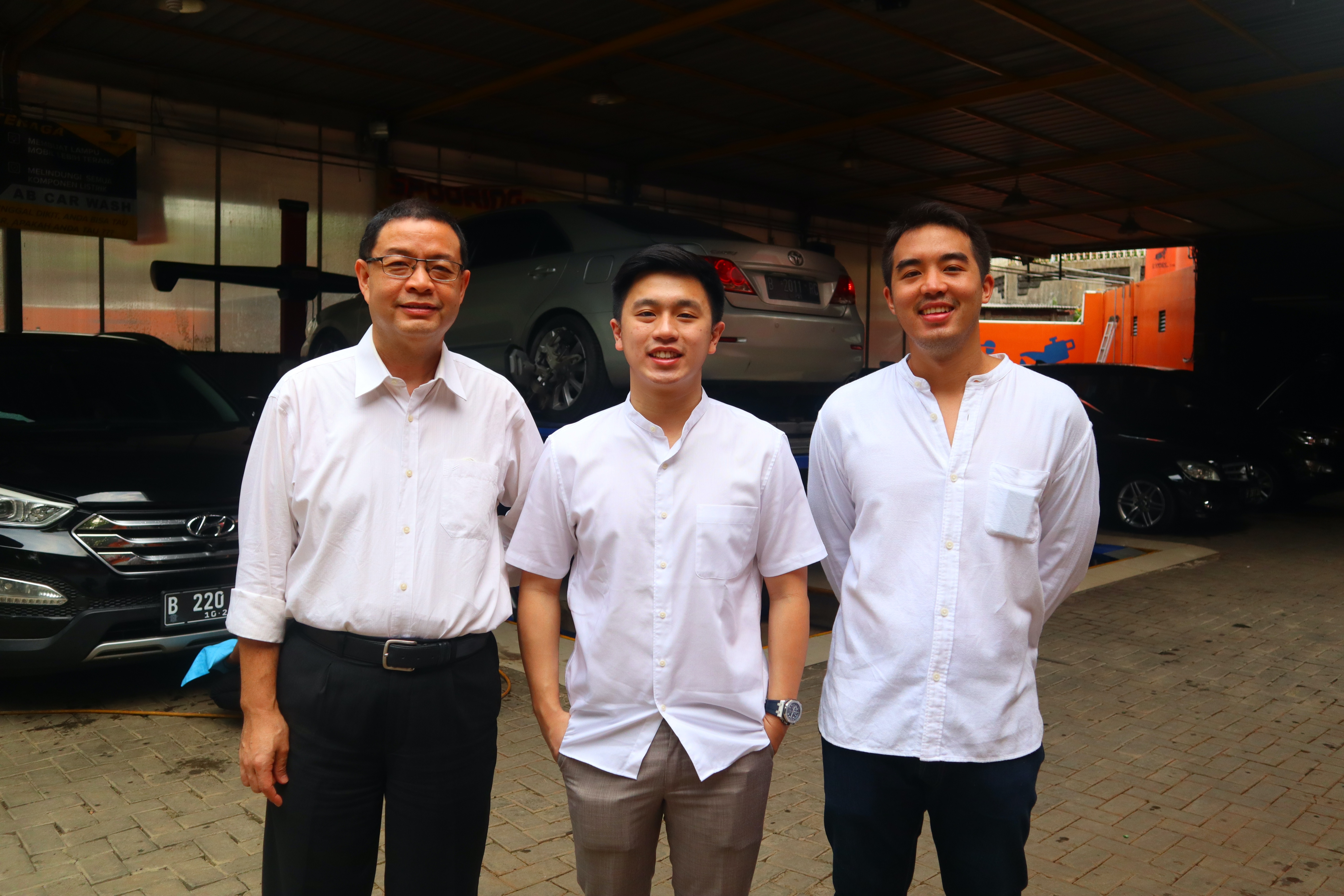 Otoklix co-founders Benny Sutedjo, Martin Reyhan Suryohusodo and Joseph Alexander Ananto standing together in a car workshop