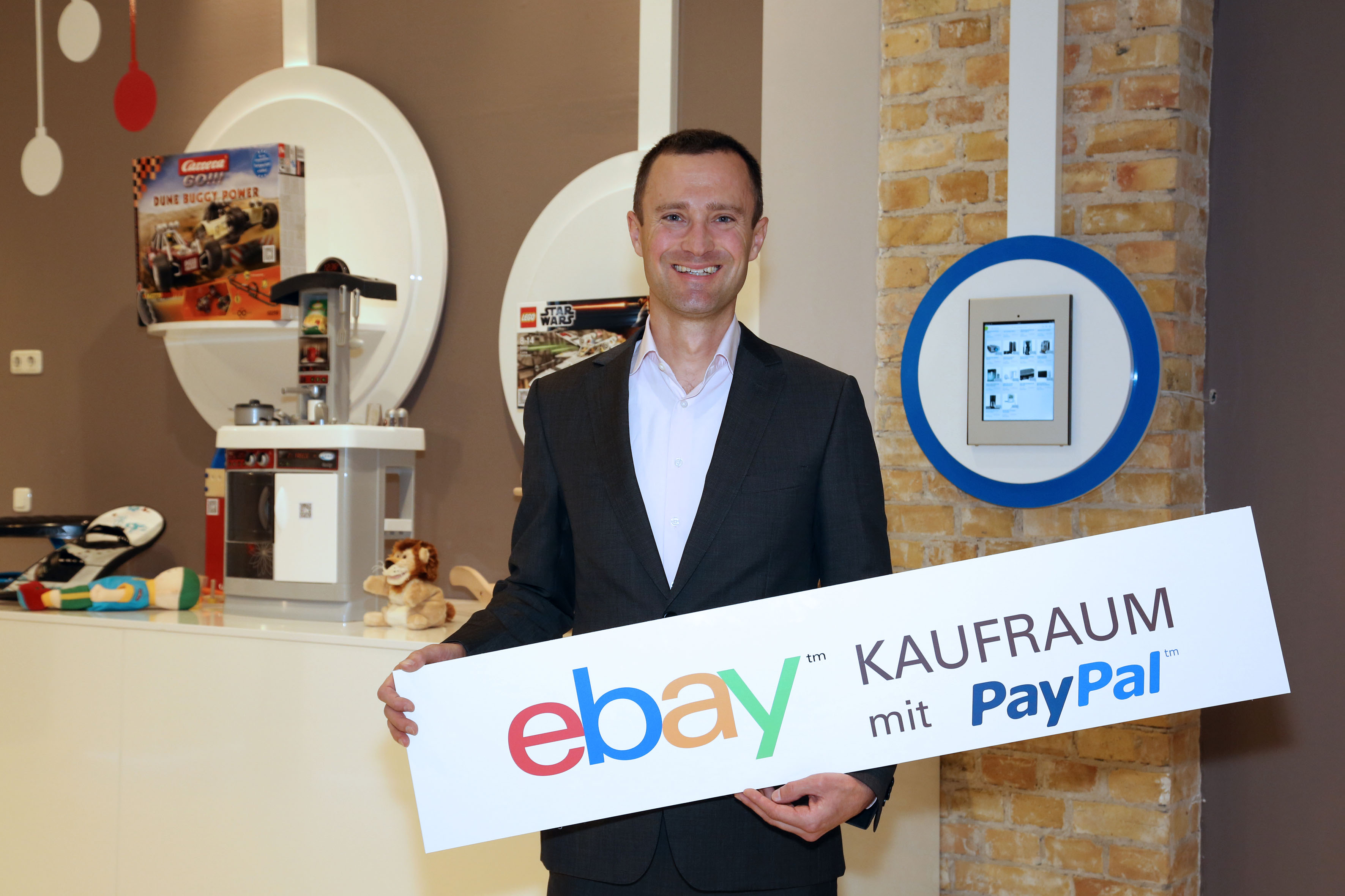 Martin Tschopp holding an eBay Kaufraum sign at the Berlin pop-up shop in December 2012