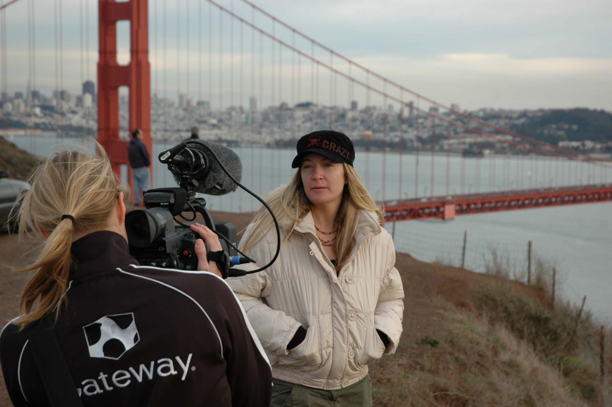 Mary Ann O’Brien in front of the Golden Gate Bridge, facing a camera operator wearing a Gateway jacket