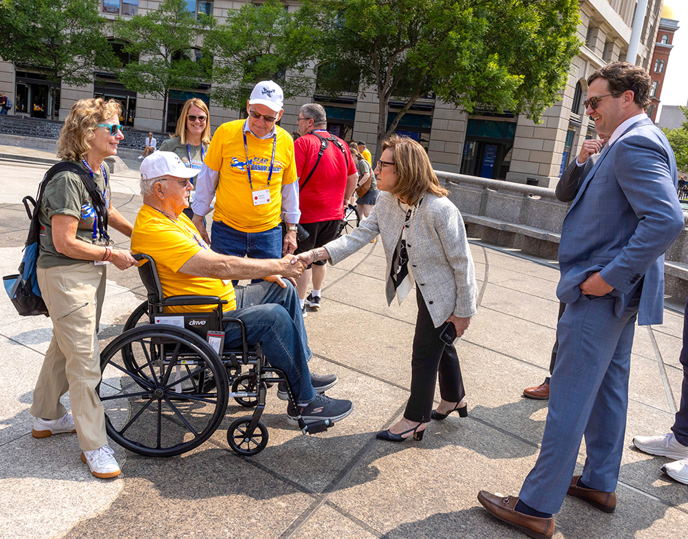 Maryann Mannen leans forward to shake hands with an Honor Flight veteran in Washington, D.C.