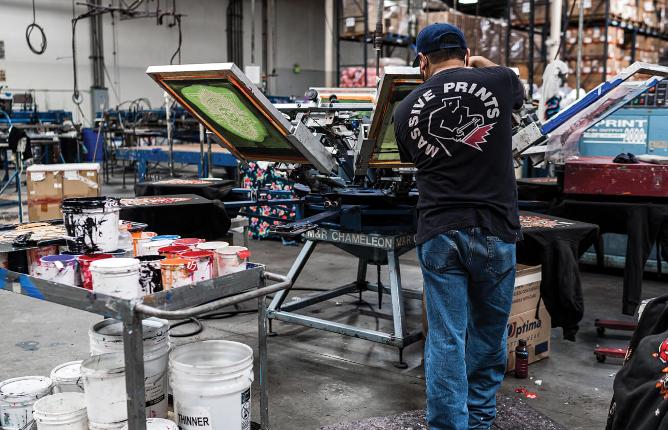 A Massive Prints worker operating a multicolor screen-printing press