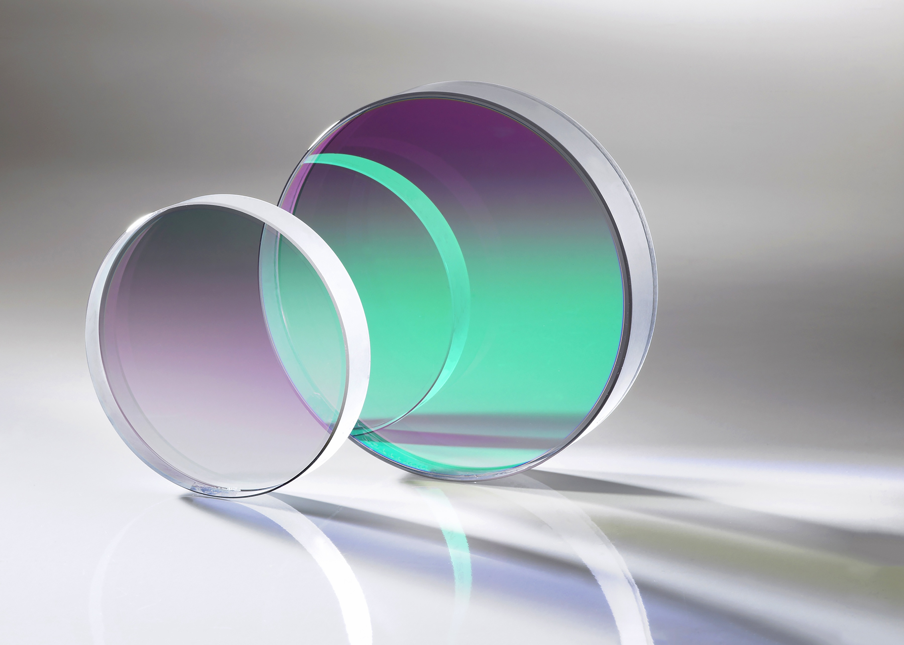 Two circular Materion optical filters reflecting green and purple light