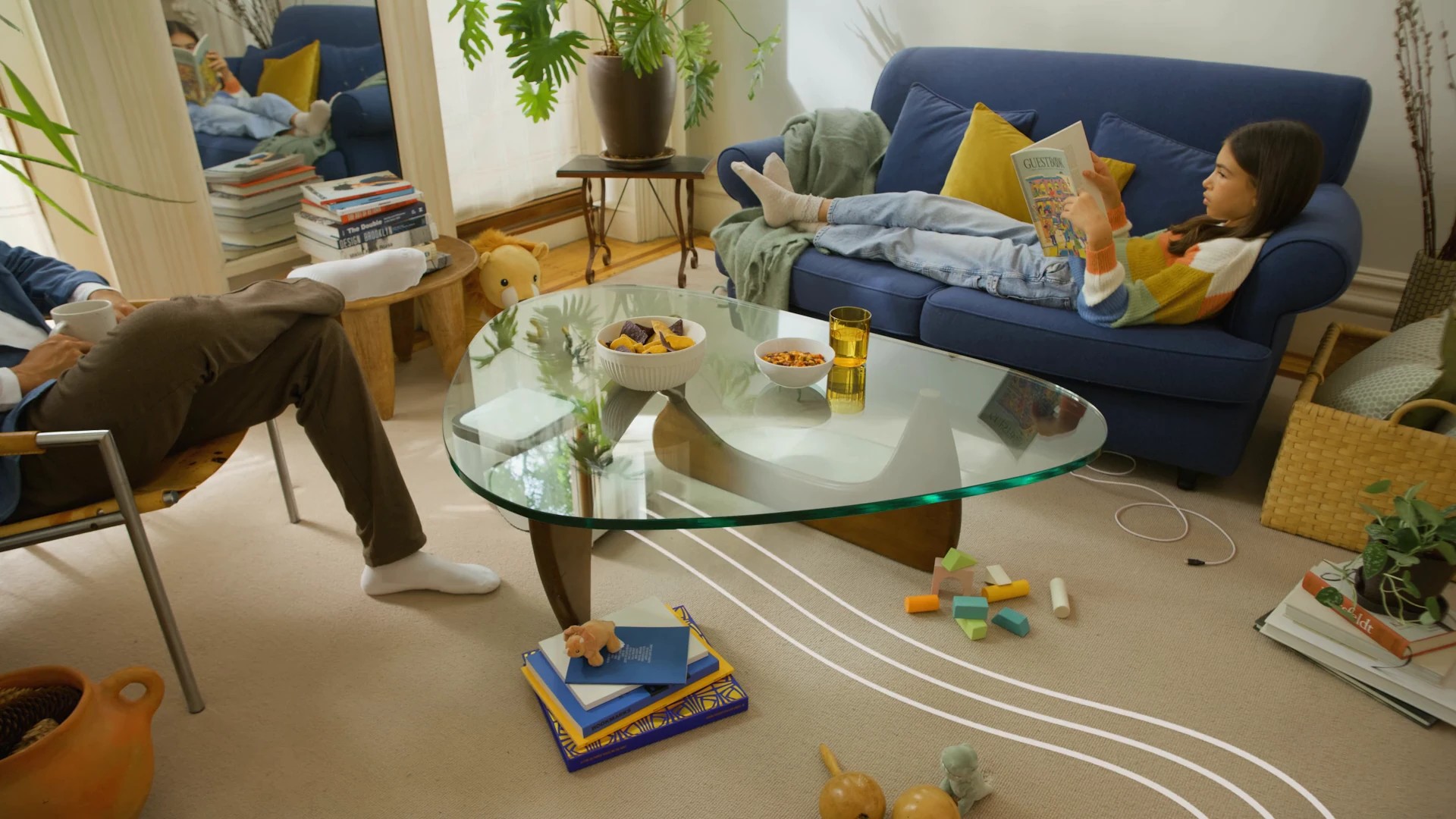A living room with a family relaxing while Matic's planned cleaning path is drawn as white lines across the floor around furniture and cables