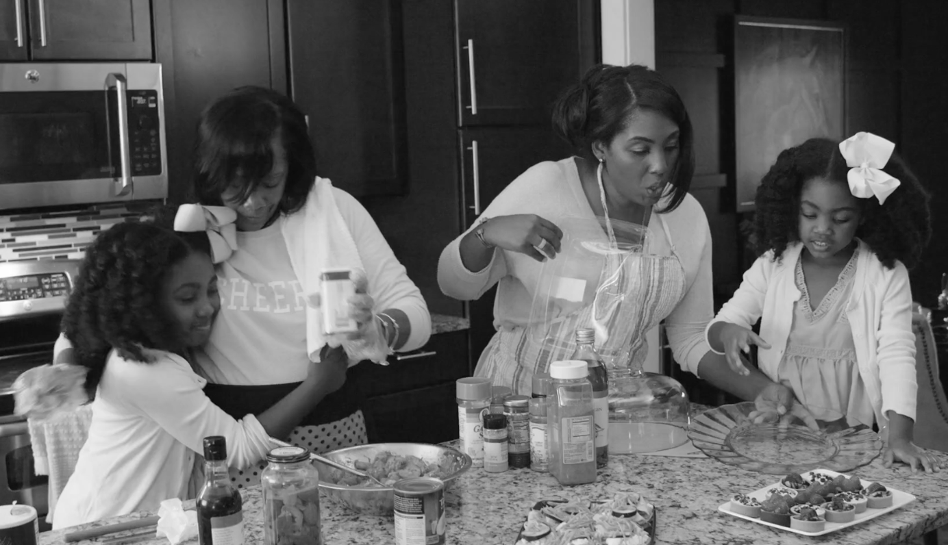 Family members baking together in a kitchen in a black-and-white Publix campaign image