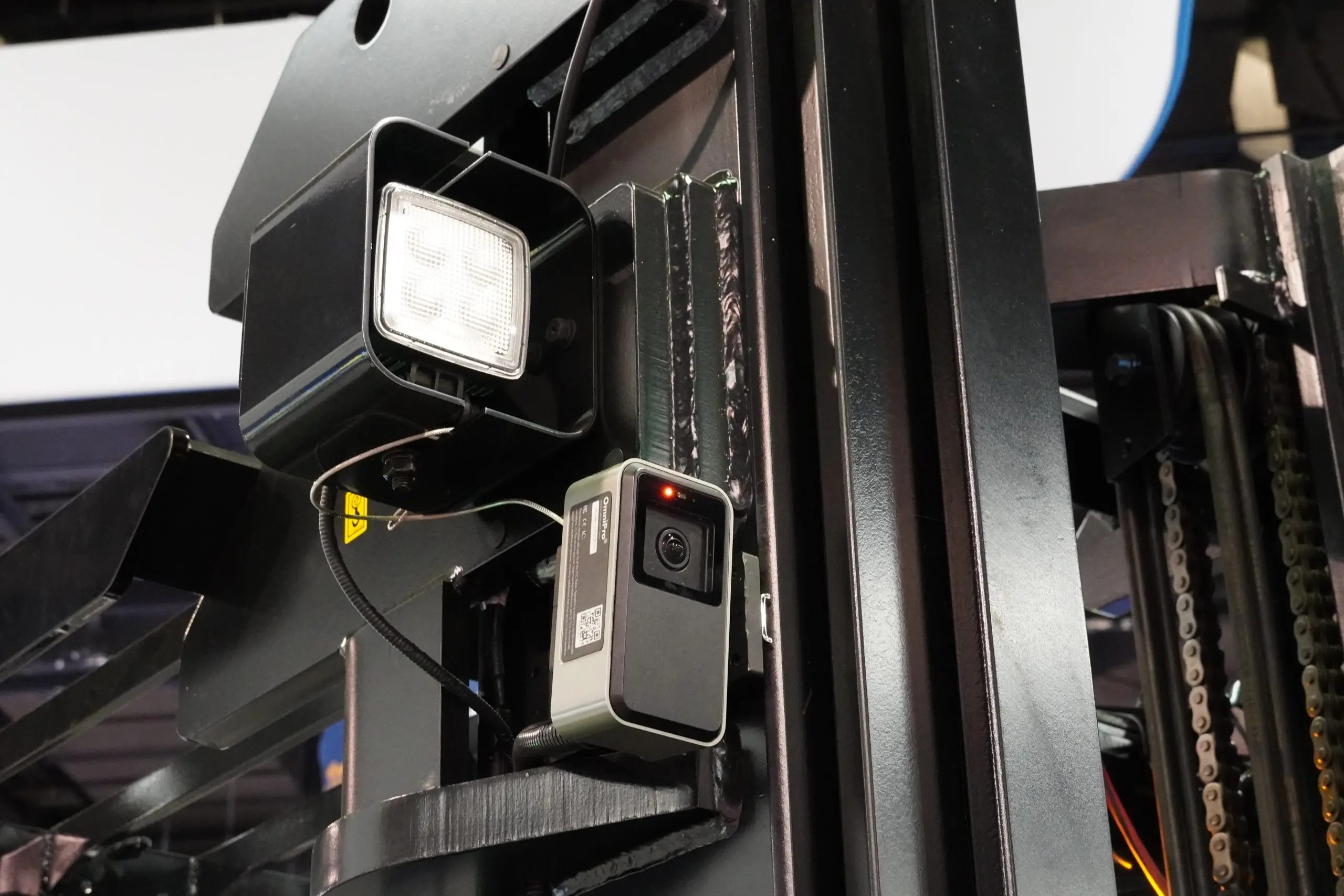 An OmniPro camera mounted beside the mast and work light of a forklift