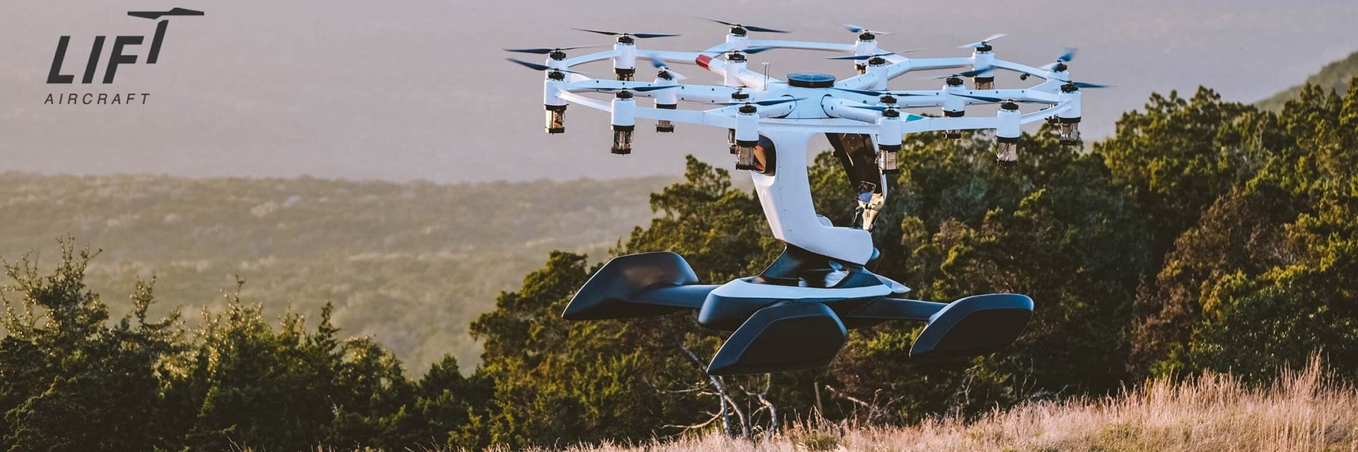 An uncrewed LIFT HEXA electric aircraft hovering over a field