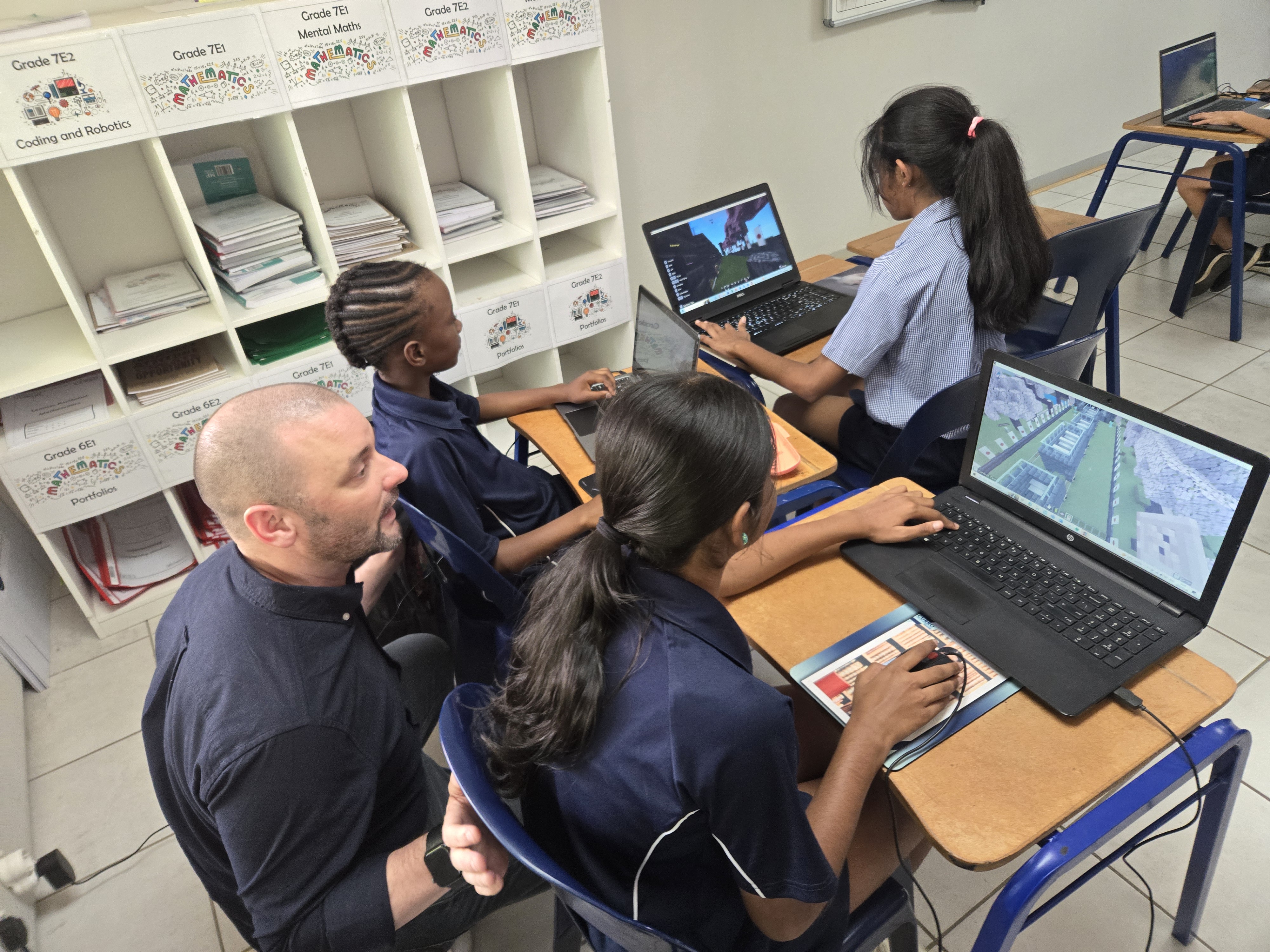 Students working on games on laptops with an instructor during an Endless summer camp