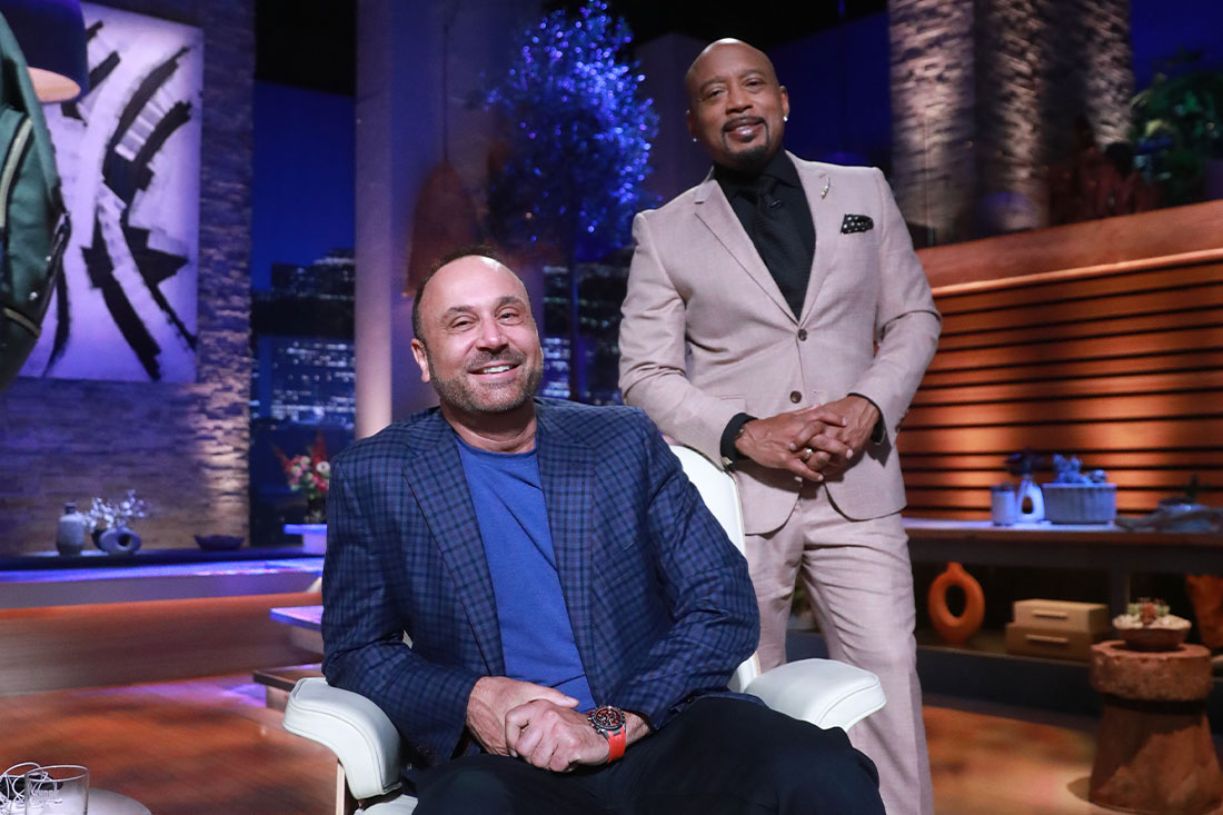 Matt Ebert seated in a blue jacket beside entrepreneur Daymond John