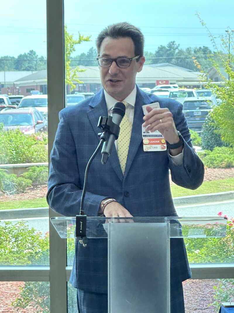 Matt Hasbrouck speaking at a transparent lectern during his farewell gathering at Meadows in 2024