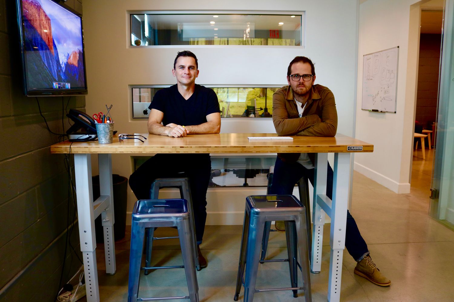 Matt Knox and Johnnie Munger seated at a wooden worktable in an office