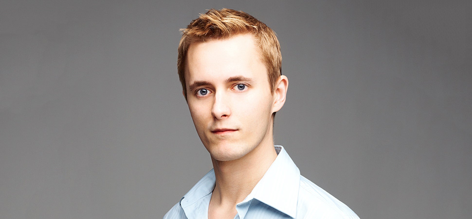 Matt Mickiewicz in a light blue shirt, photographed against a gray background