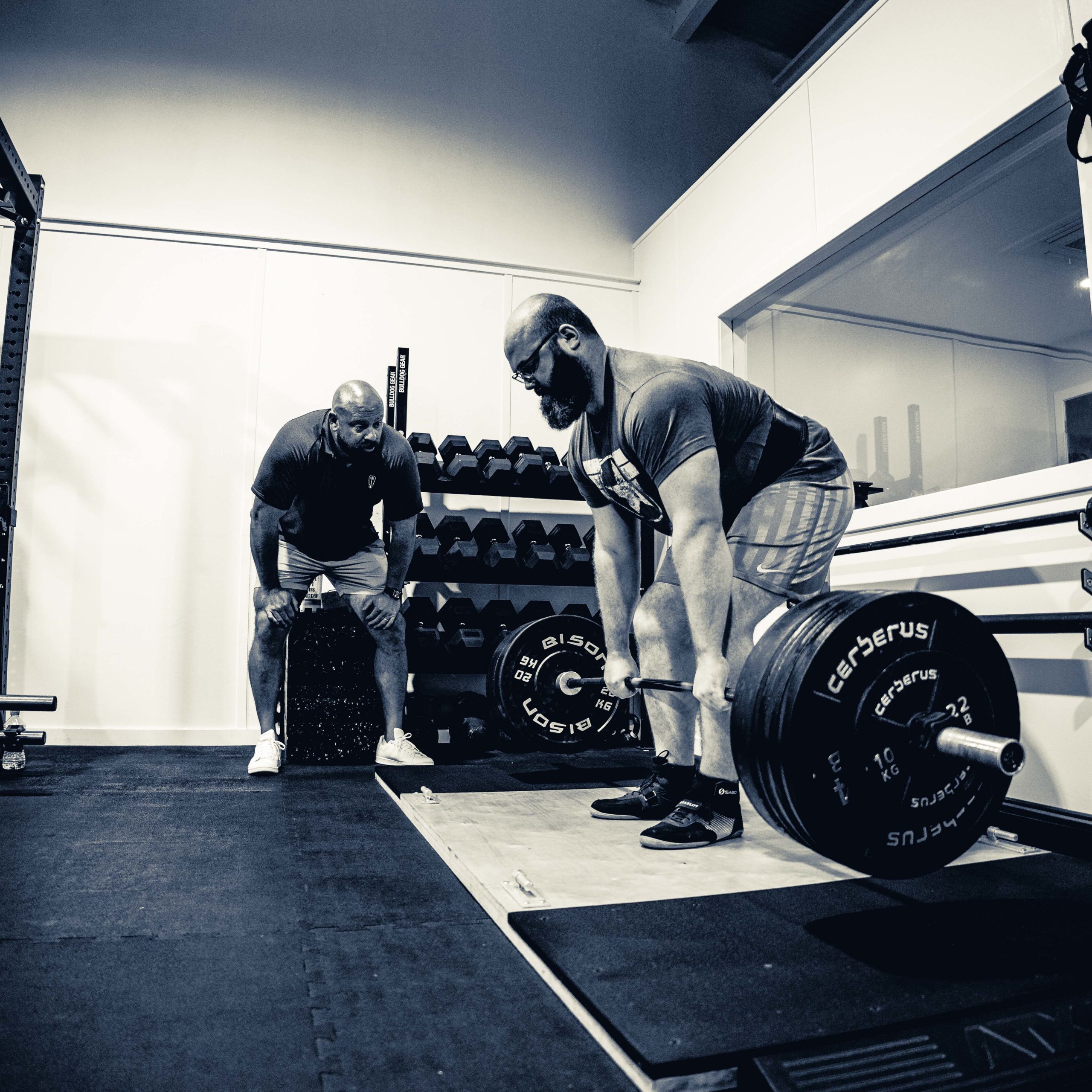 Matt Reynolds watching a lifter perform a deadlift in a gym