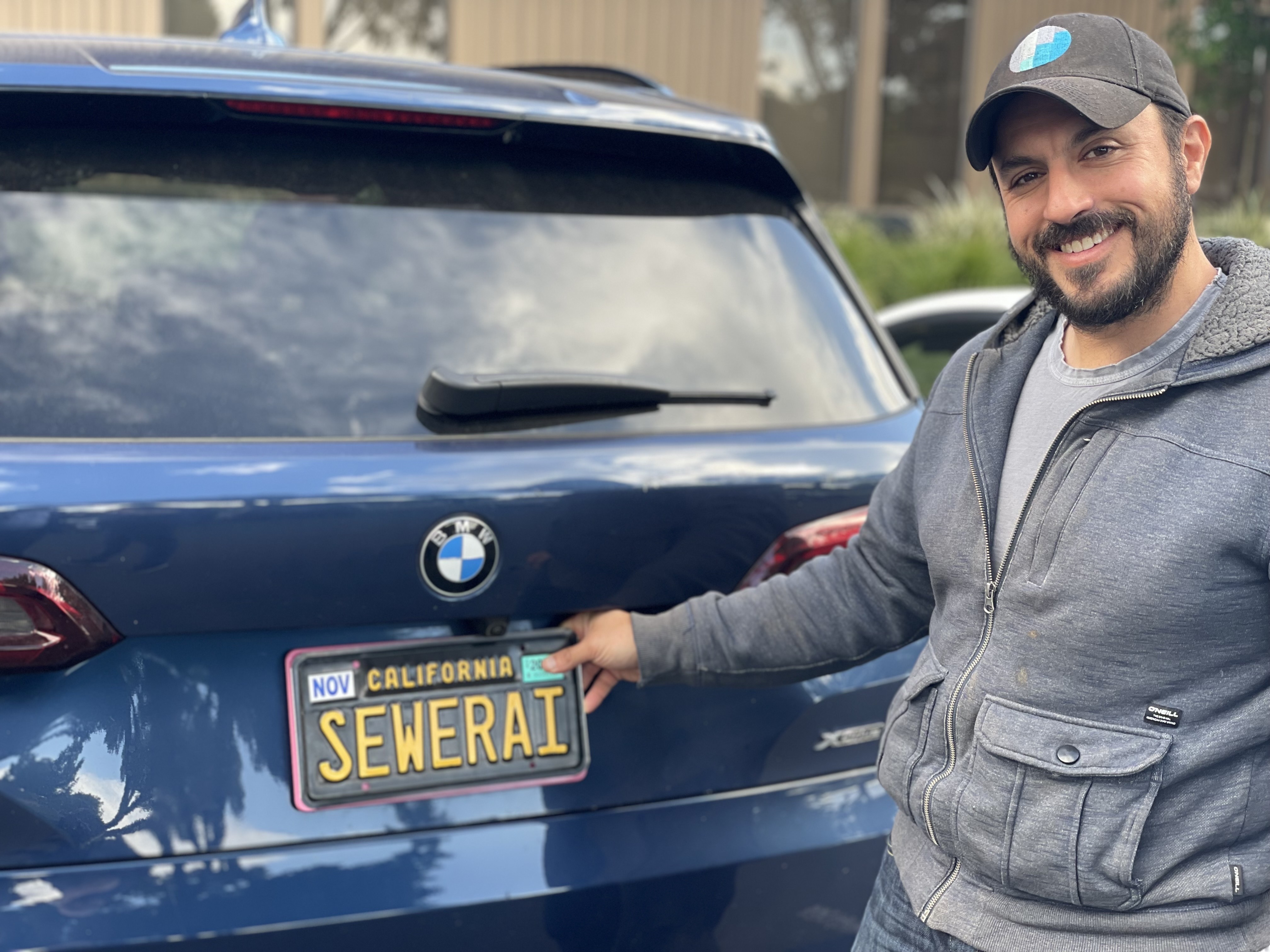 Matt Rosenthal smiling beside a car with a California license plate reading SEWERAI