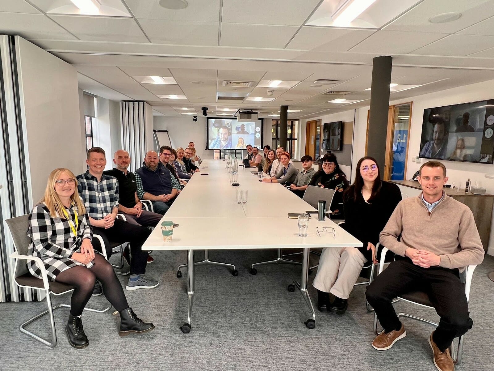 Supply Pilot colleagues gathered around a long meeting table, with remote colleagues on video screens