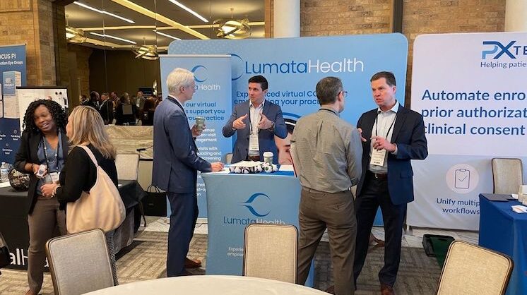 Lumata Health team members speaking with attendees at a professional conference booth