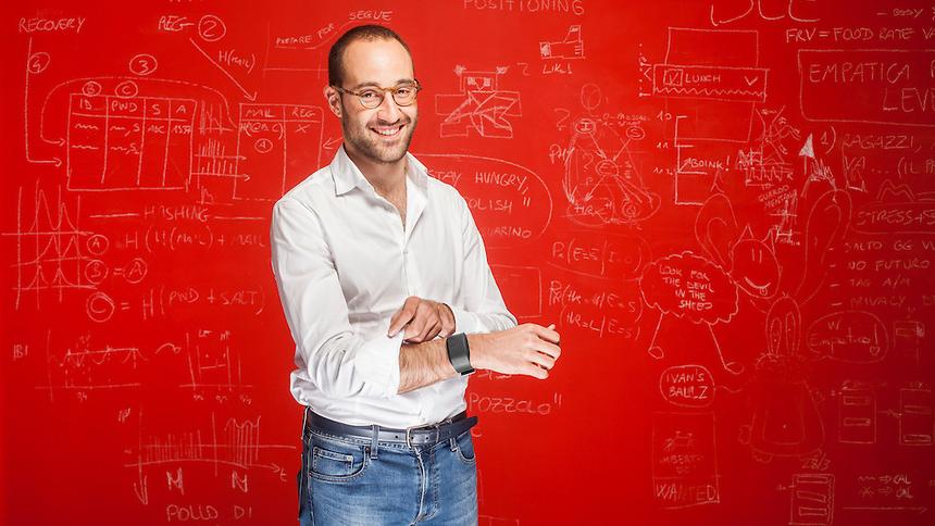 Matteo Lai wearing a wristband in front of a red wall covered with handwritten diagrams