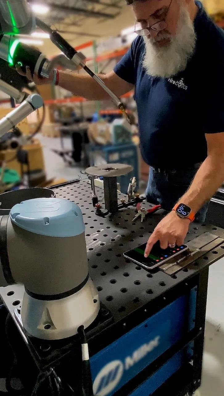 Matthew Bush guiding a collaborative welding robot while using the Beacon app on a phone