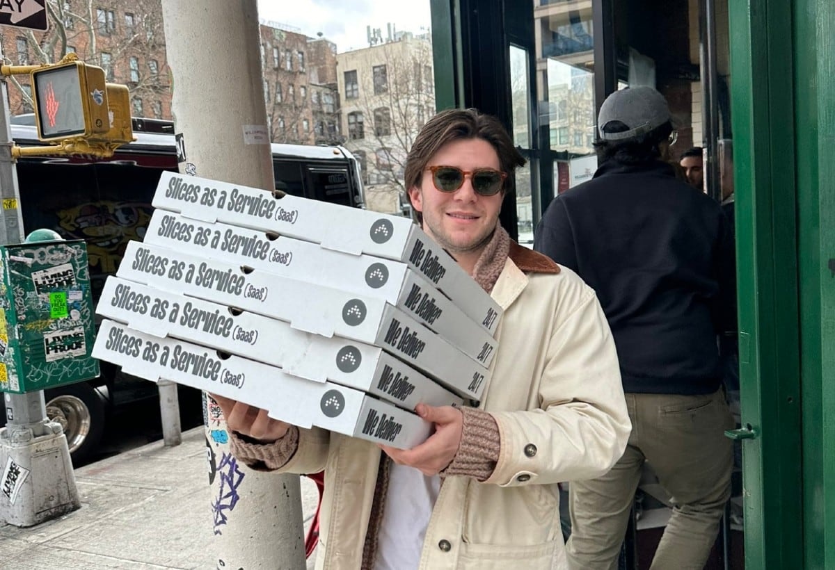 Matthew Parkhurst carrying a stack of Antimetal pizza boxes on a city sidewalk.