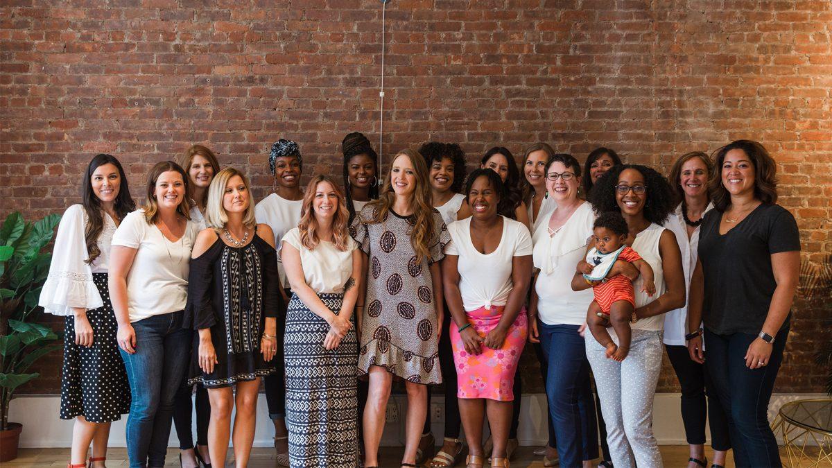 Kate Ryder standing with an early Maven Clinic team in a brick-walled office