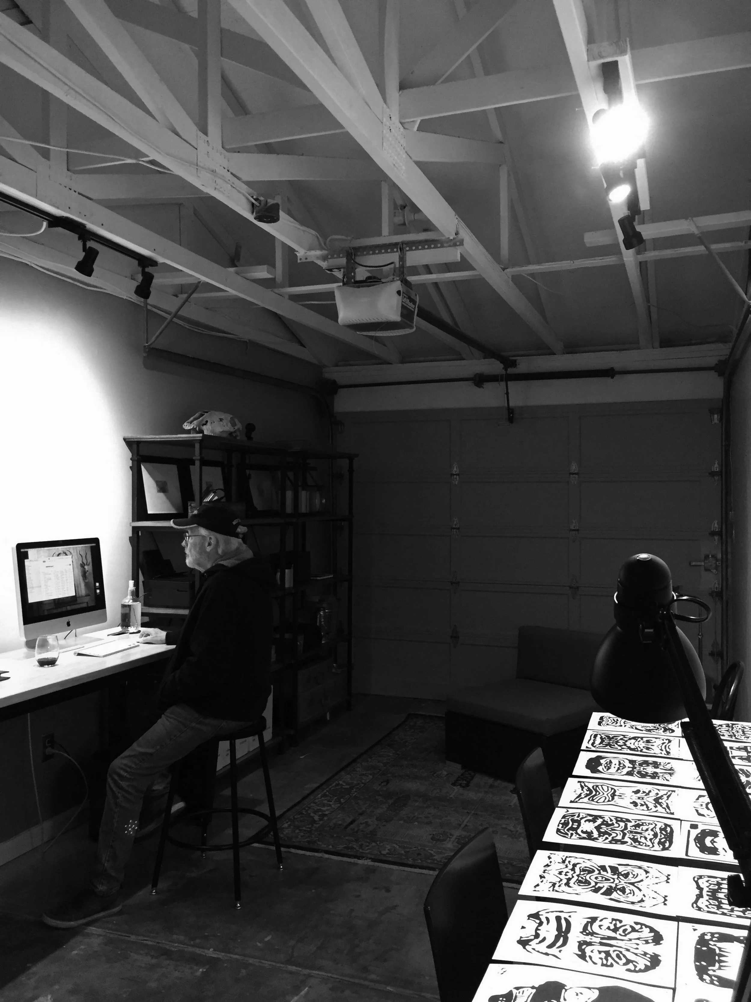 Max Seabaugh seated at his computer, with Cargoyles sketches spread across a nearby table