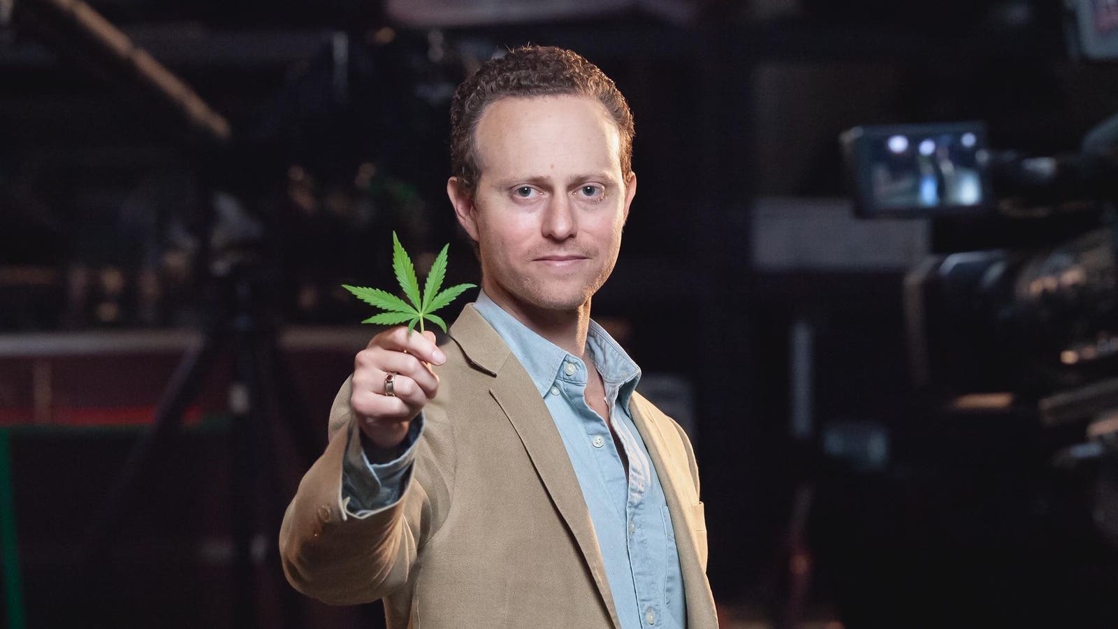 Max Simon holding a cannabis leaf in a studio setting