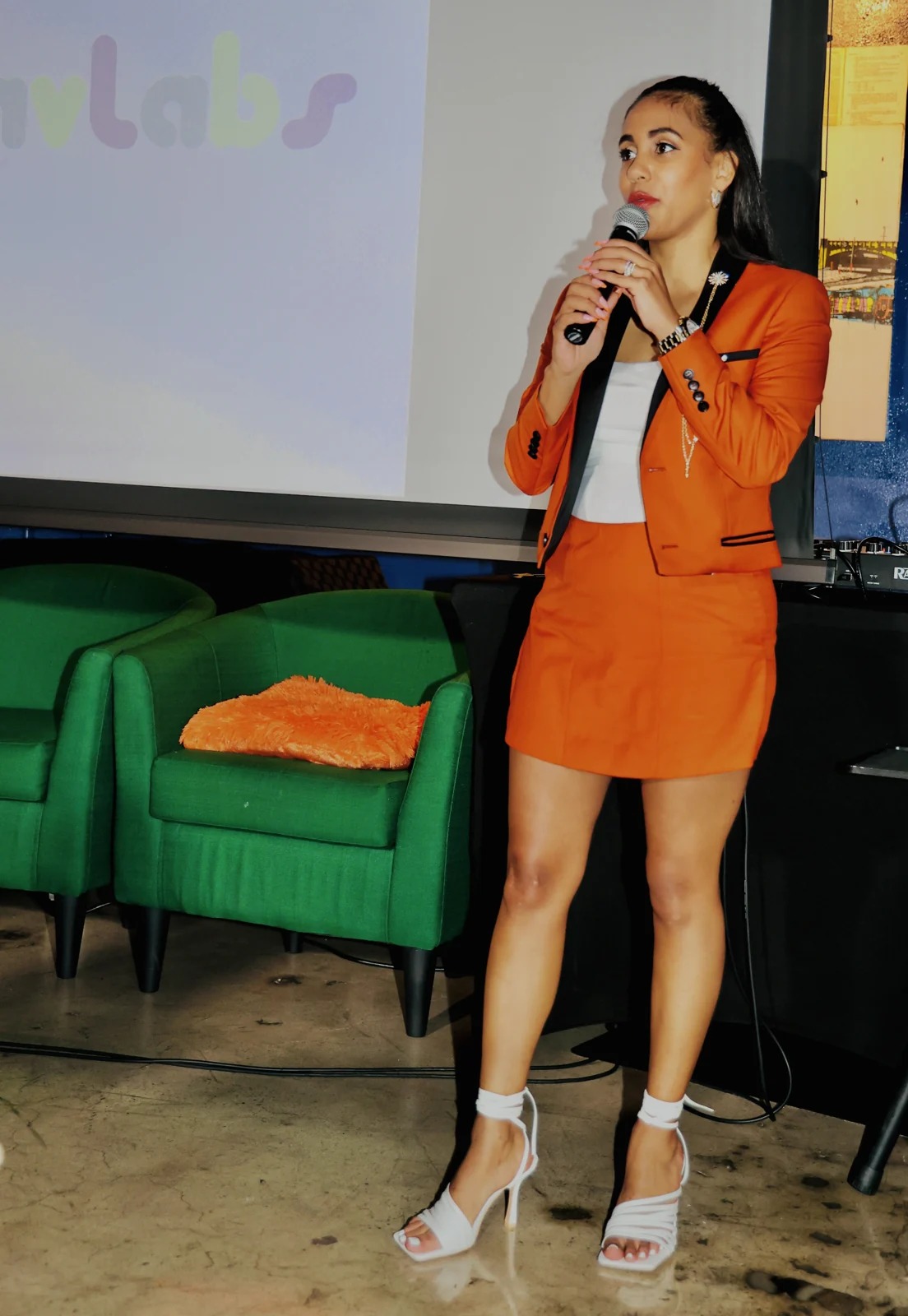 Maya Elz Davis speaking into a microphone at a Yuhmmy event