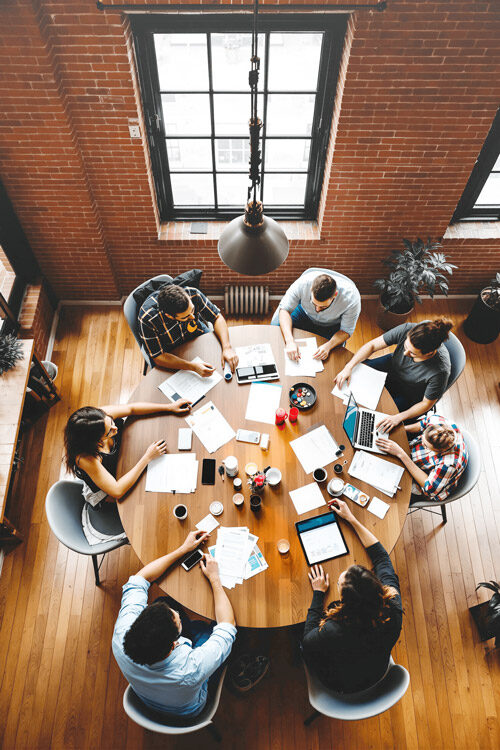 Overhead view of a creative team gathered around a meeting table