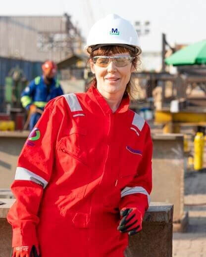 Worker wearing McDermott protective clothing, hard hat and safety glasses at an industrial site