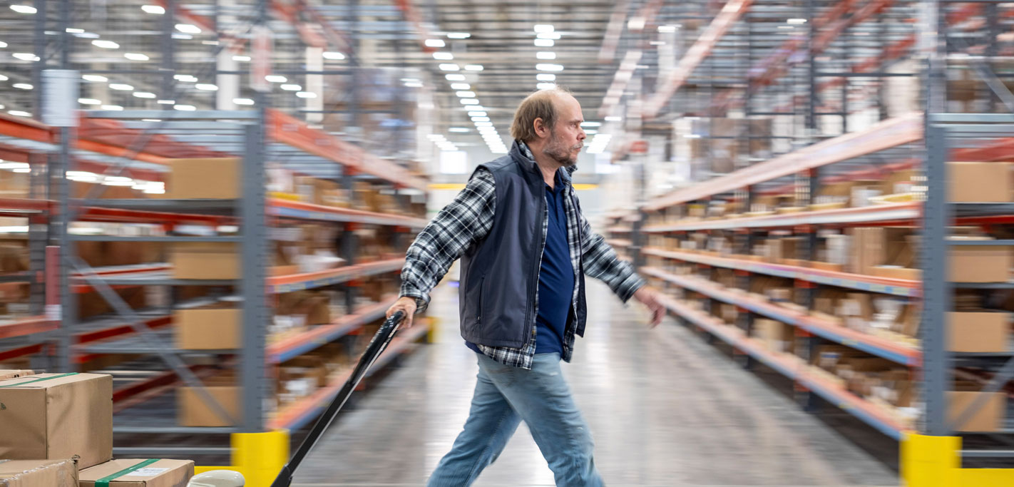 Worker pulling a pallet jack through a McKesson warehouse