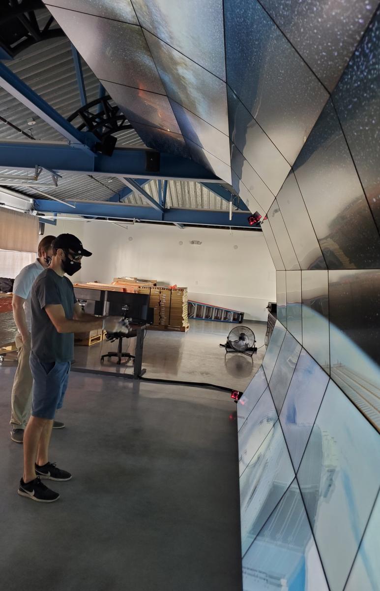 Anthony Piro testing Carnegie Observatories’ curved VizLab display, beneath screens showing astronomical imagery
