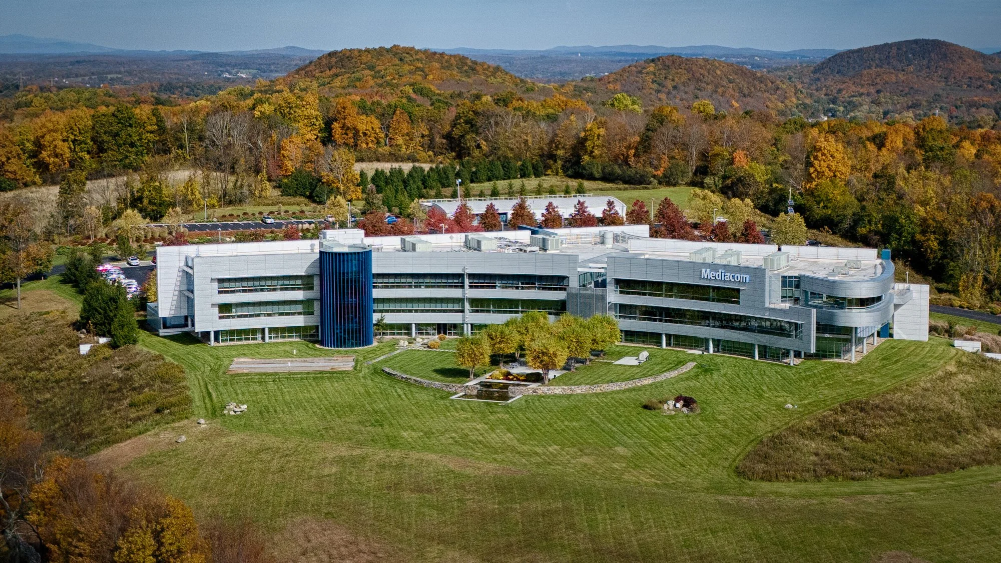Aerial view of Mediacom’s curved headquarters building surrounded by autumn trees