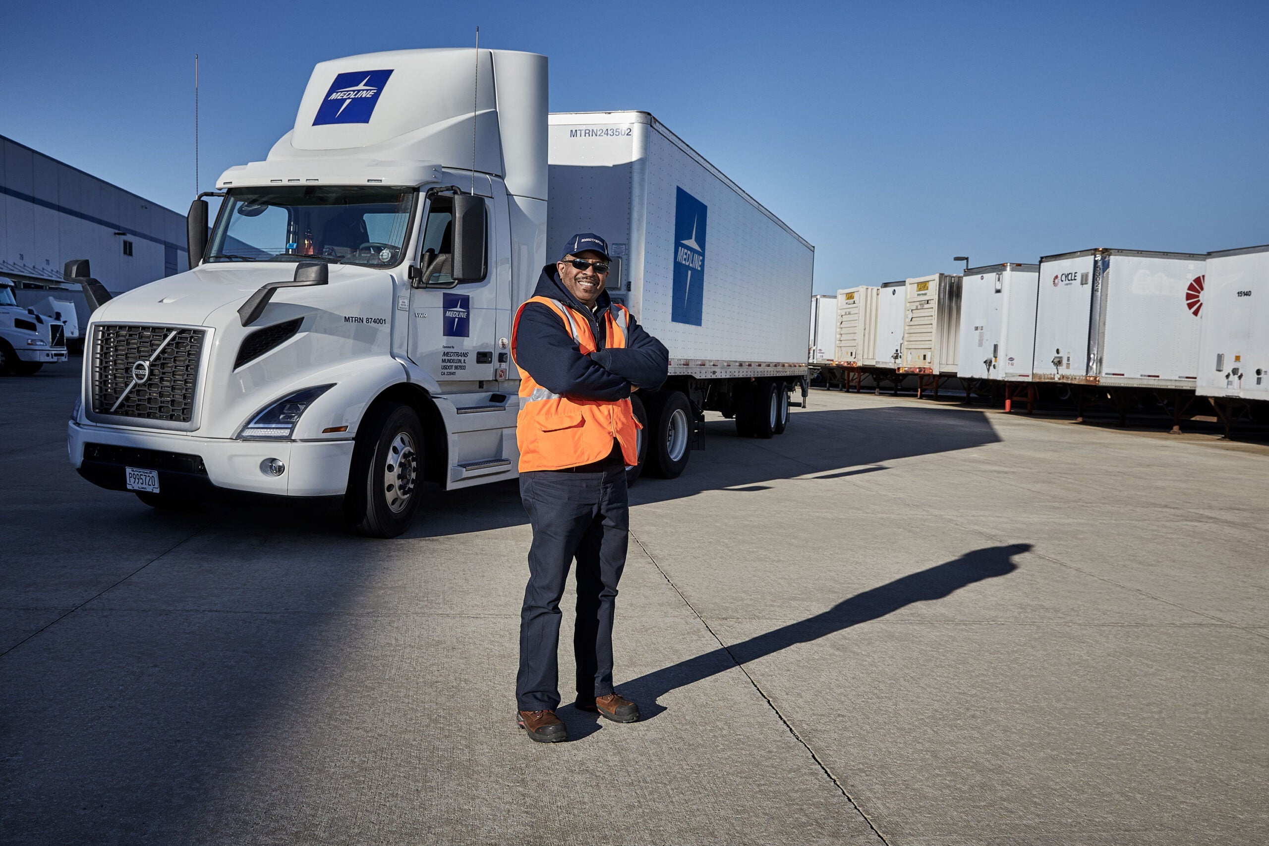 A MedTrans driver beside a Medline delivery truck