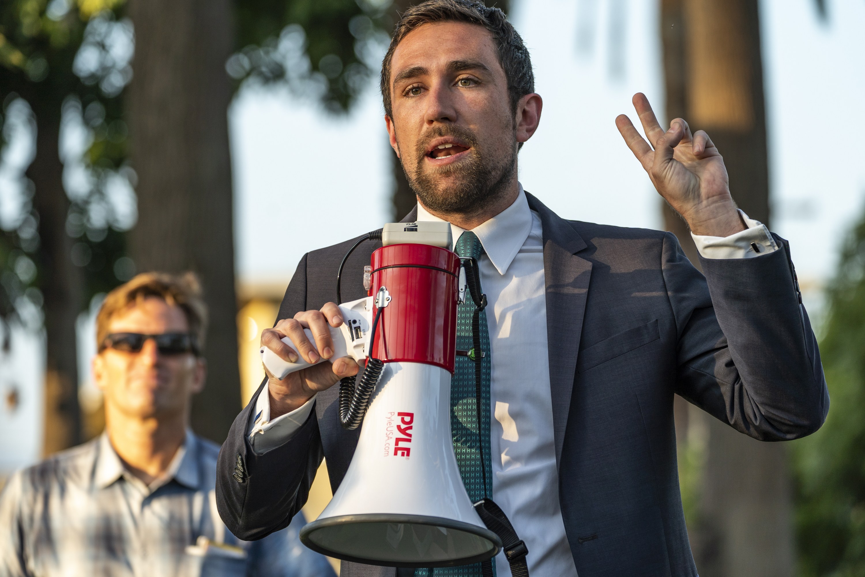 Kevin Paffrath speaking into a megaphone at an outdoor California campaign rally in 2021