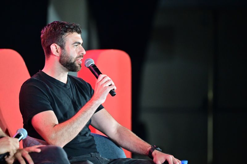 Meiran Galis speaking into a microphone during a conference panel