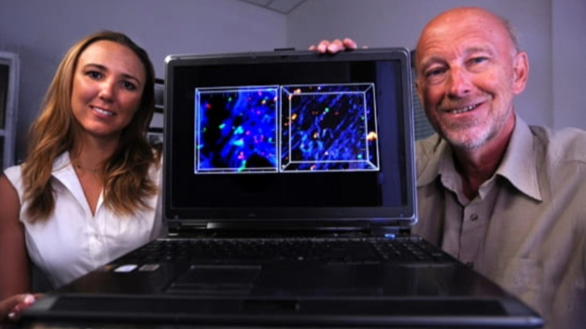 Melanie Matheu and her doctoral mentor Michael Cahalan holding a laptop displaying research images
