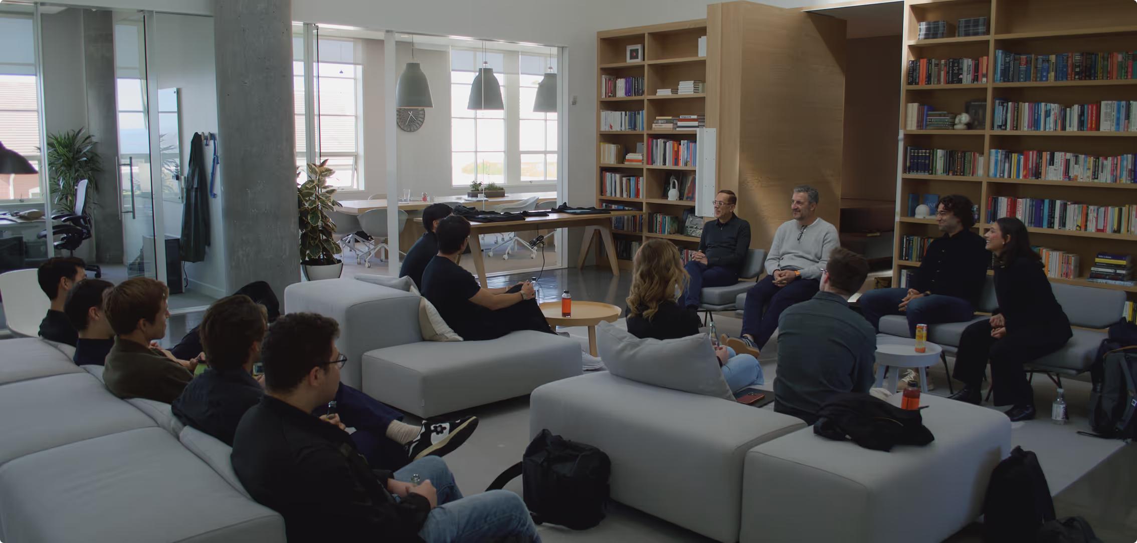 Netic colleagues gathered in a book-lined room, with Melisa Tokmak seated at the far right