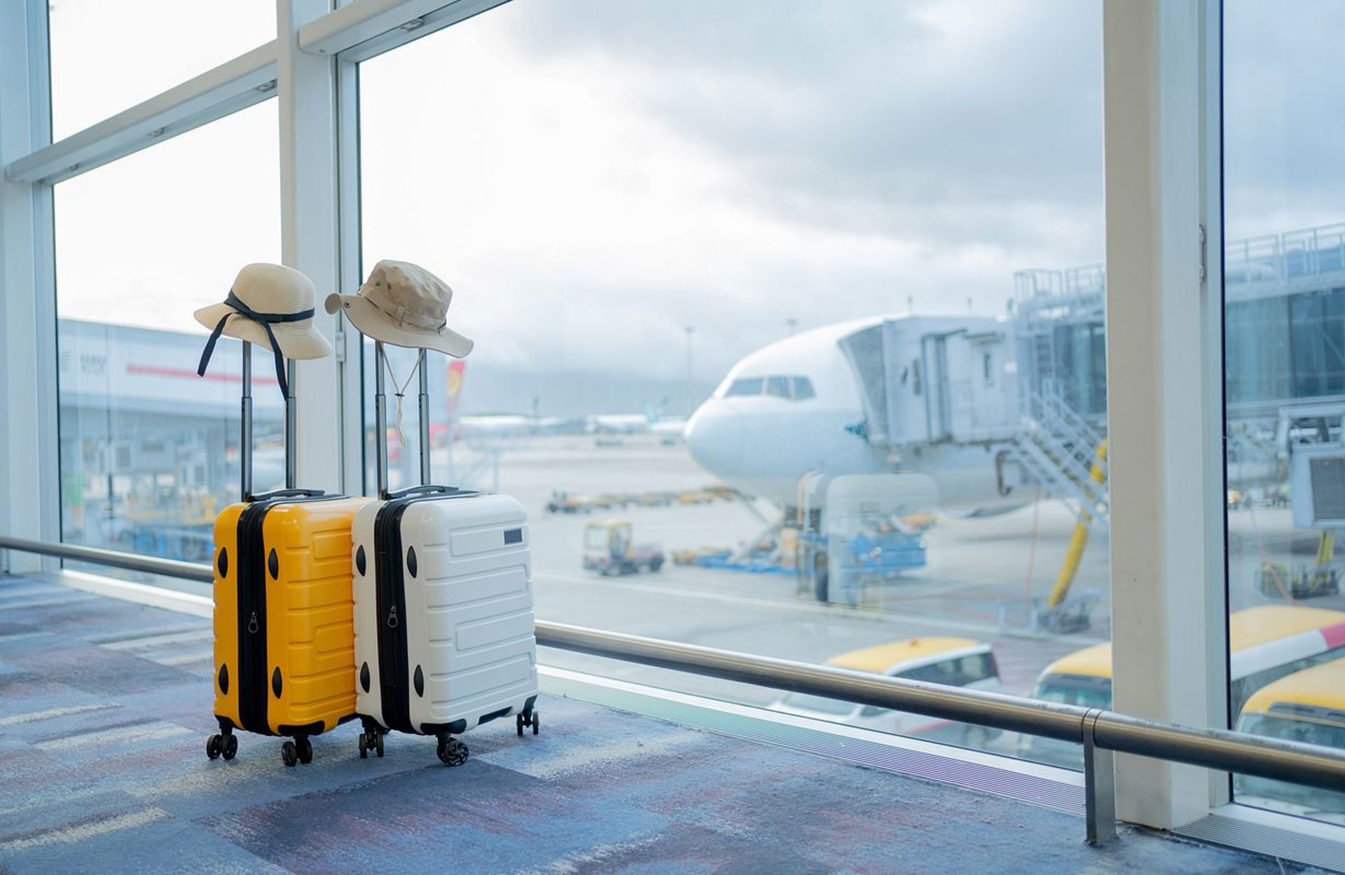 Two suitcases beside an airport window with an aircraft waiting outside