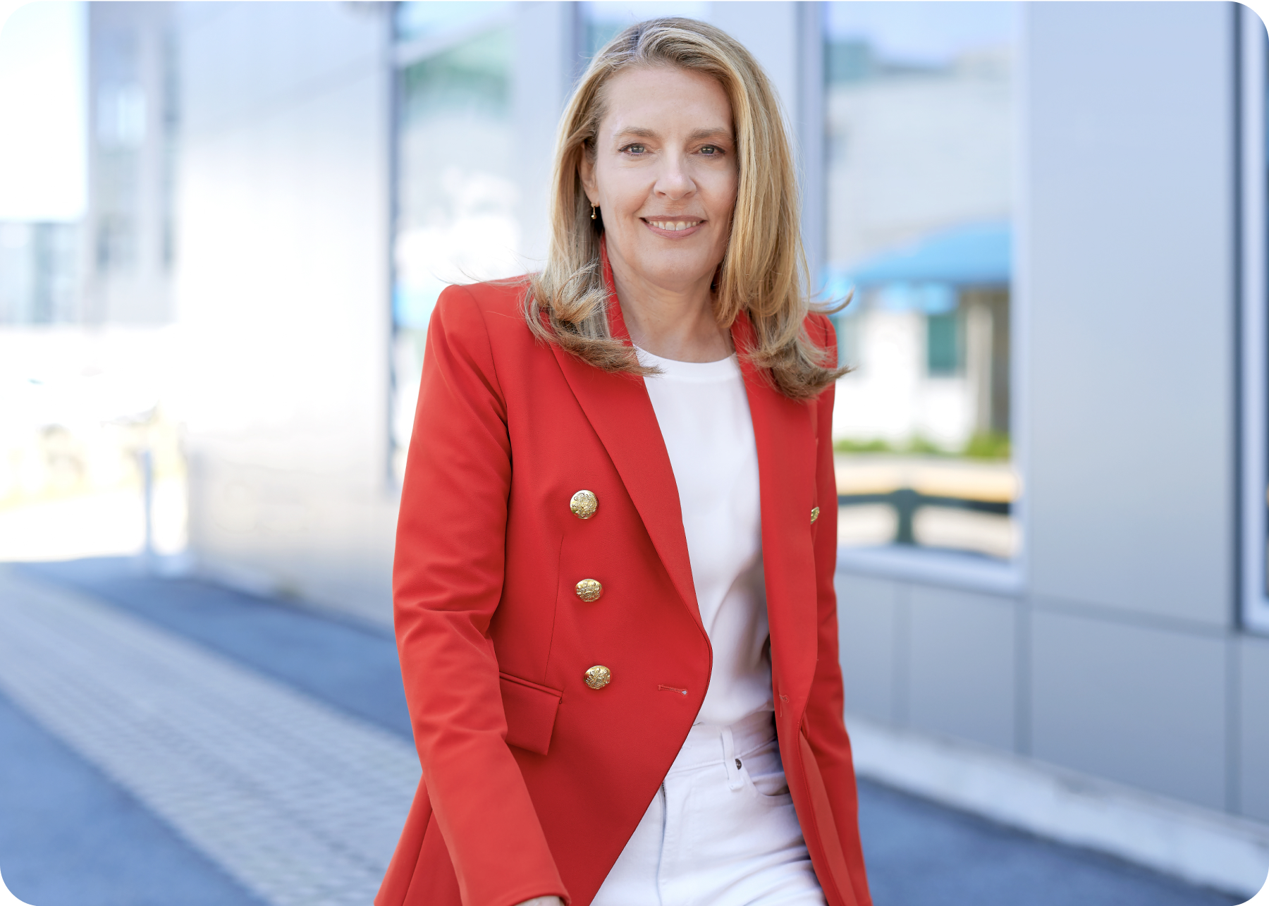 Melissa Smith in a red blazer, standing beside the windows of a WEX office