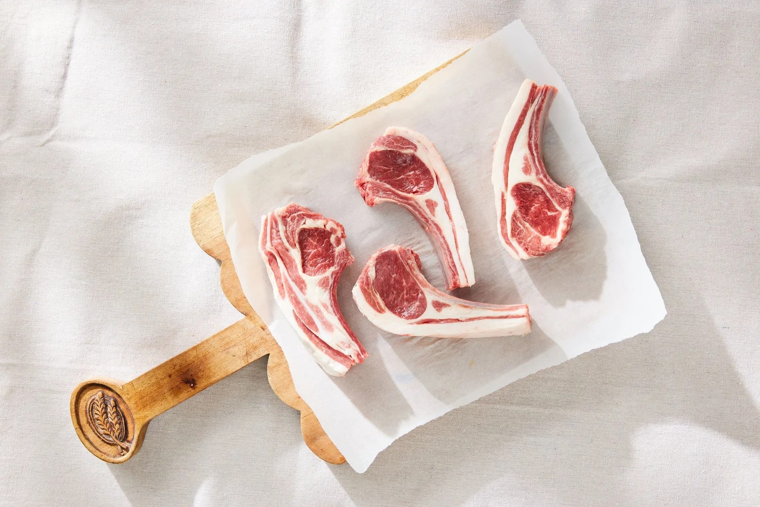Four lamb cutlets arranged on a wooden board, showing the marbling and eye of meat MEQ's technology measures