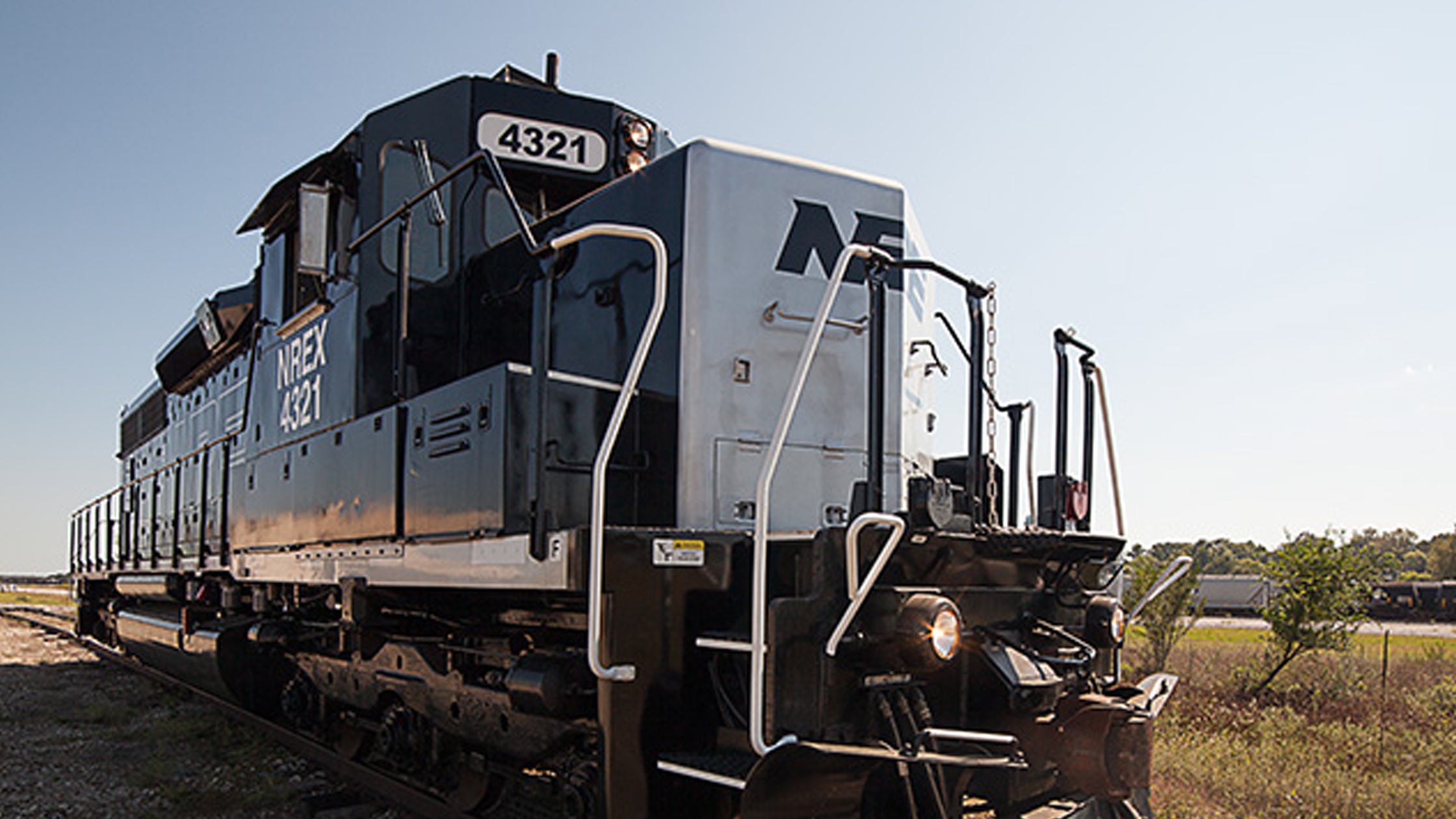 A blue and white National Railway Equipment locomotive in a rail yard