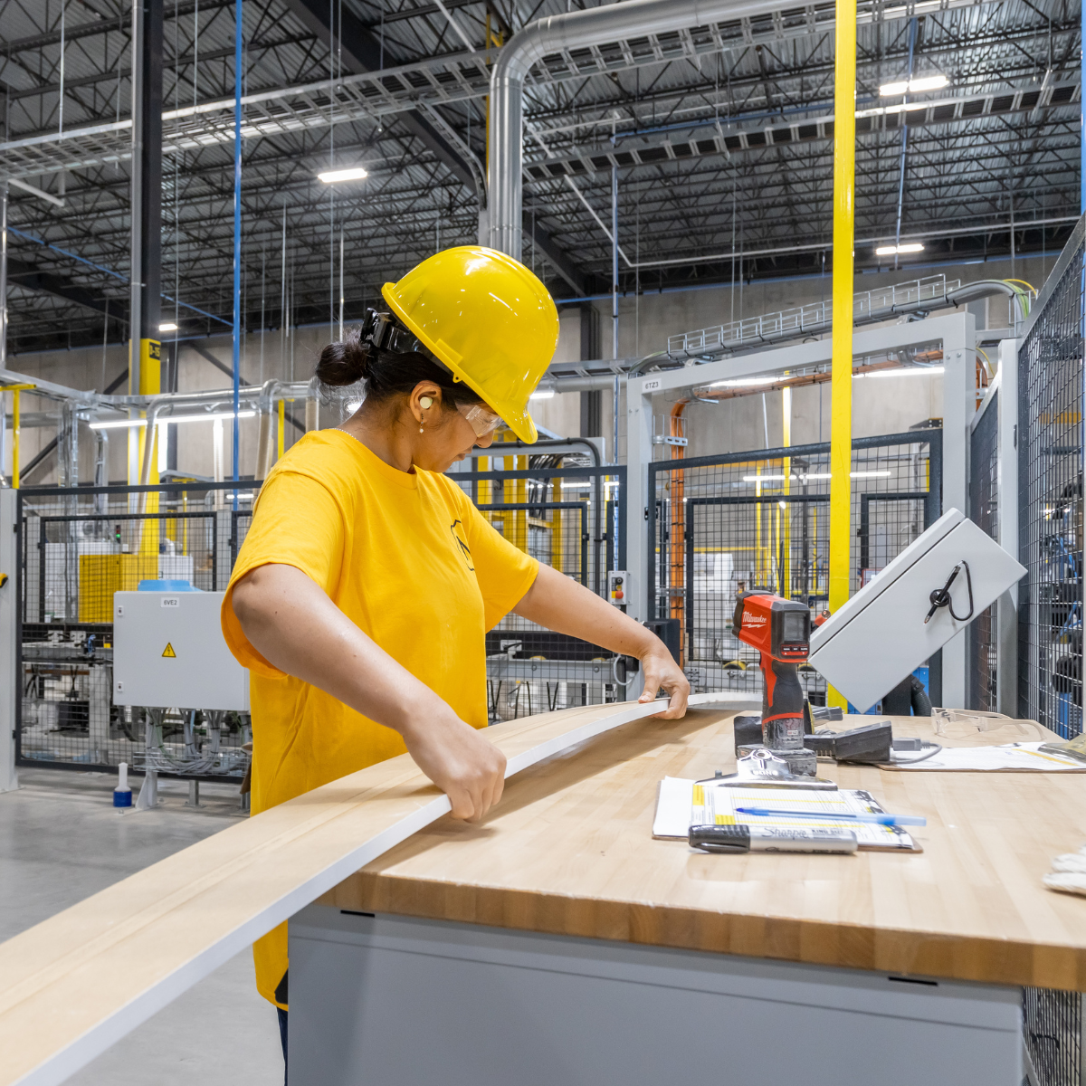 A Metrie employee measuring a length of trim in a modern manufacturing facility