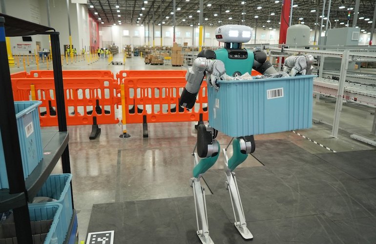 Agility Robotics Digit carrying a blue tote in an industrial facility