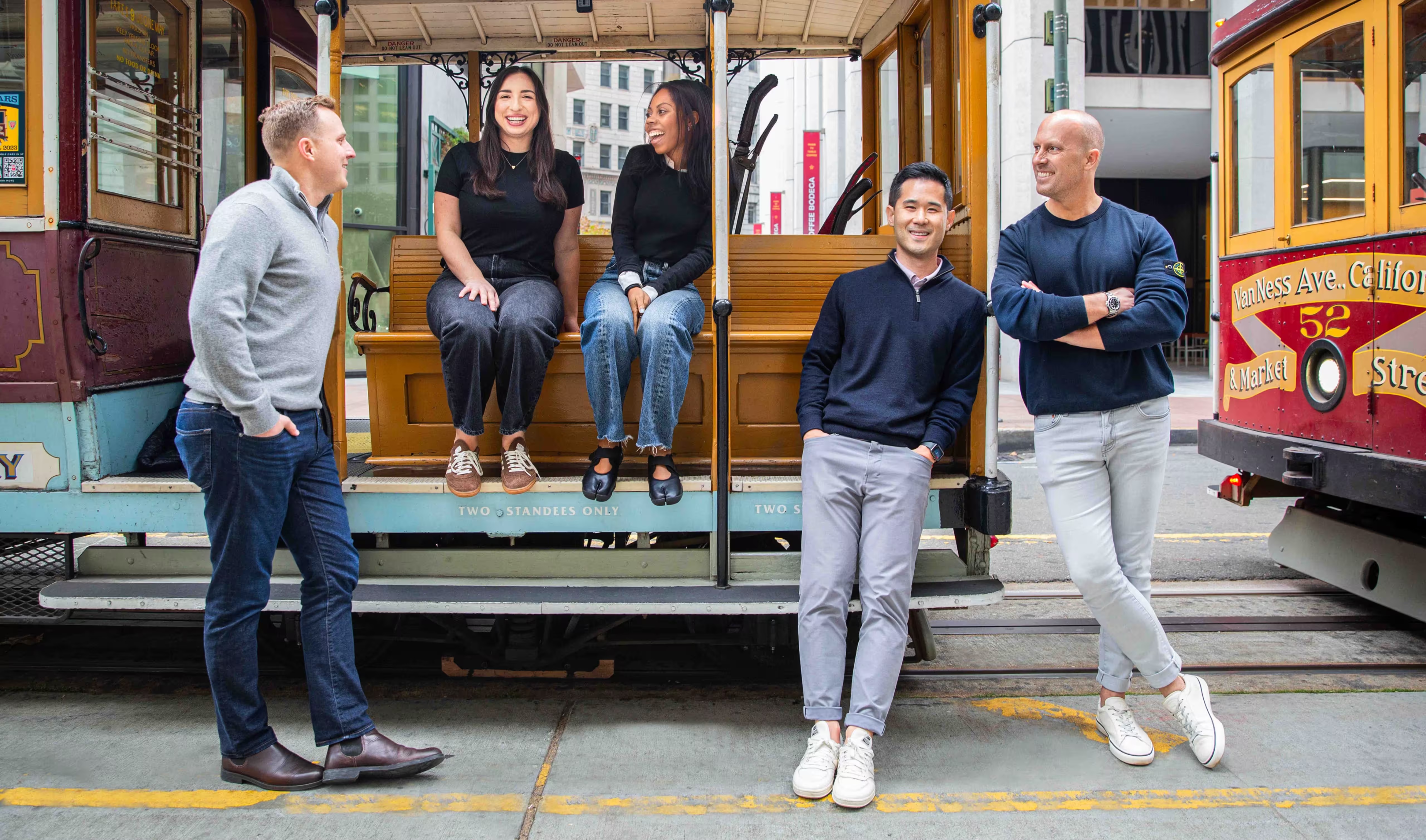 Five MGV team members smiling beside a San Francisco cable car